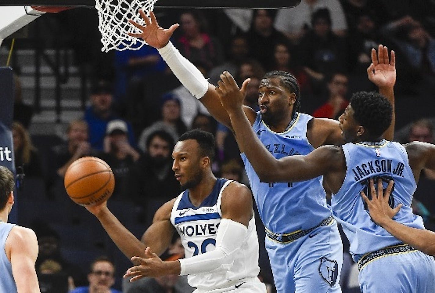 Wolves guard Josh Okogie passed the ball under the basket while being guarded by Grizzlies forward Solomon Hill, center, and forward Jaren Jackson Jr. during the first half Sunday.