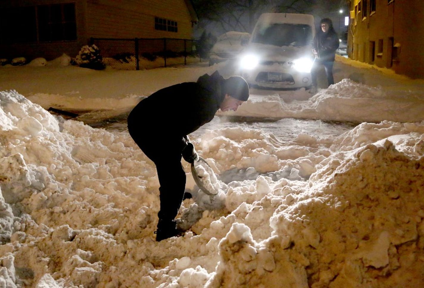 Good Samaritan Doug Milek took over shoveling with a large frying pan for Santiago Lopez, rear right, whose vehicle was stuck in his apartment's unplowed parking lot Tuesday, Jan. 23, 2018, in Minneapolis, MN.