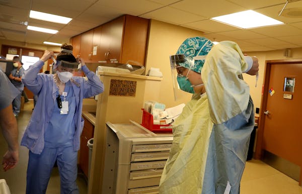Healthcare workers don PPE before phoning a COVID-19 patient in an ICU at St. Paul's Bethesda Hospital in May 7.