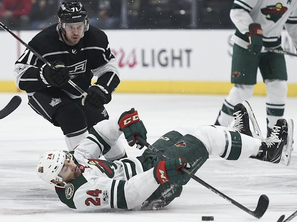 Minnesota Wild defenseman Matt Dumba falls to the ice in front of of Los Angeles Kings center Torrey Mitchell during the first period of an NHL hockey
