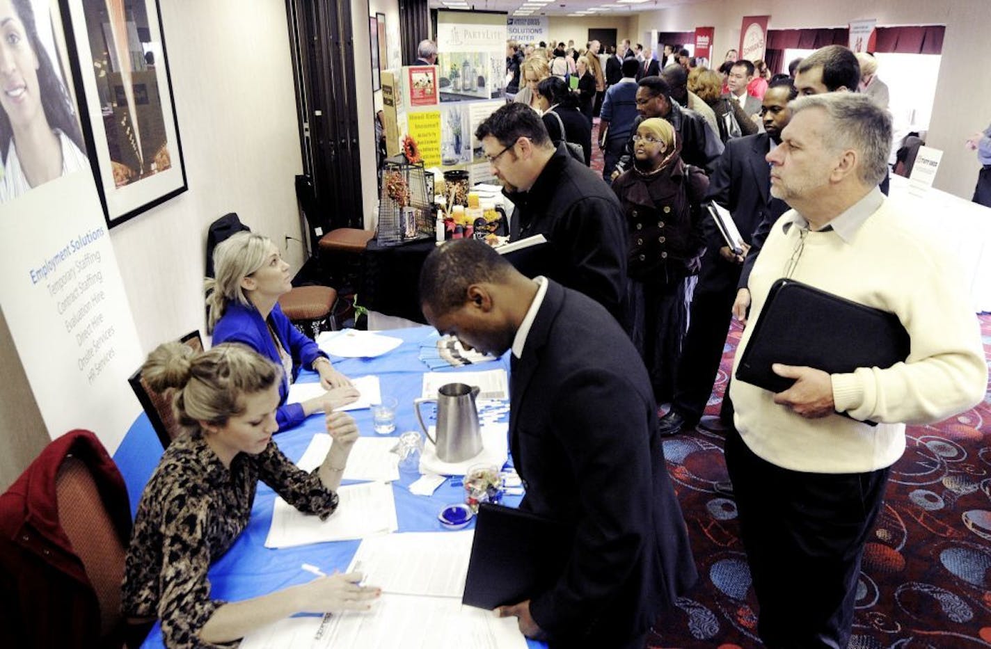 Job seekers attend the Minneapolis Career Fair held Wednesday, Nov. 2, 2011, in Bloomington, Minn. Fewer people applied for unemployment benefits last week, a positive sign that the job market is picking up a bit.