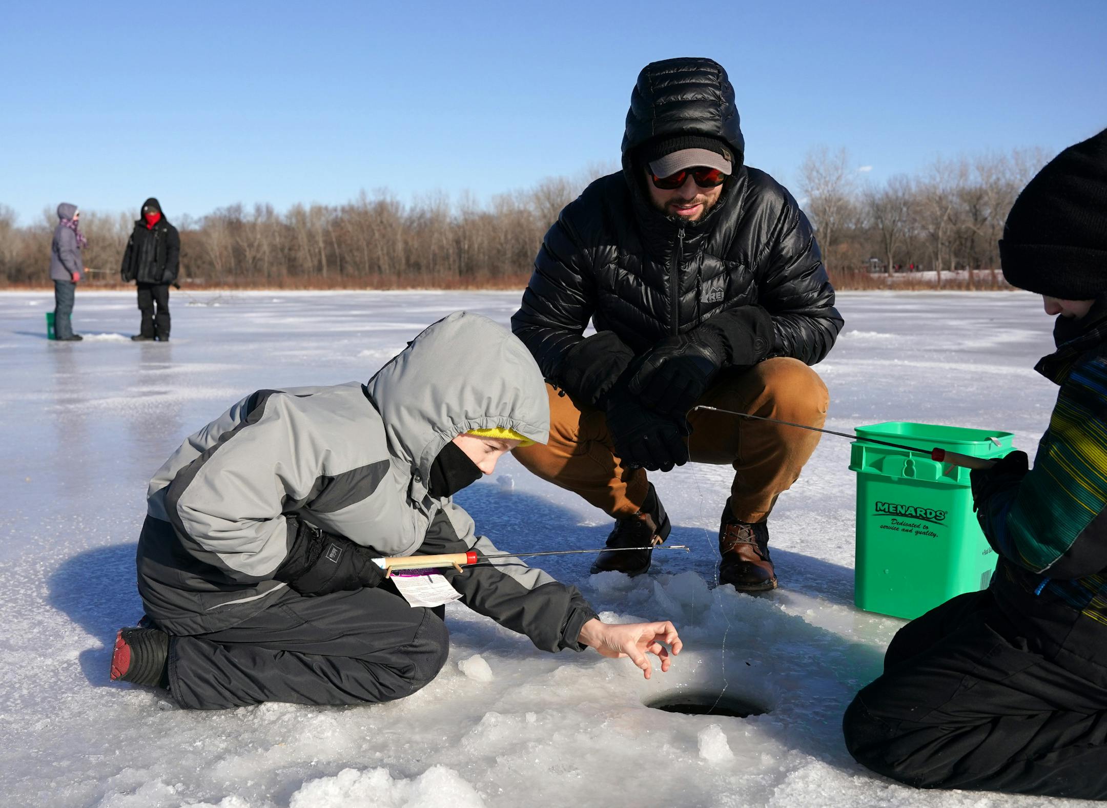 Erich Nell of Minneapolis watched as his stepsons Sullivan Maland, 6, and Harrison Maland, 9, tried their hand at ice fishing during Winter Trails day Saturday. ] ANTHONY SOUFFLE • anthony.souffle@startribune.com Attendees got to try their hand at a host of free winter activities, including ice fishing, during Winter Trails Day Saturday, Jan. 11, 2020 at Fort Snelling State Park in St. Paul, Minn.