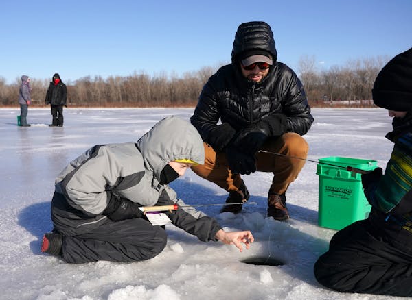 Erich Nell of Minneapolis watched as his stepsons Sullivan Maland, 6, and Harrison Maland, 9, tried their hand at ice fishing during Winter Trails day
