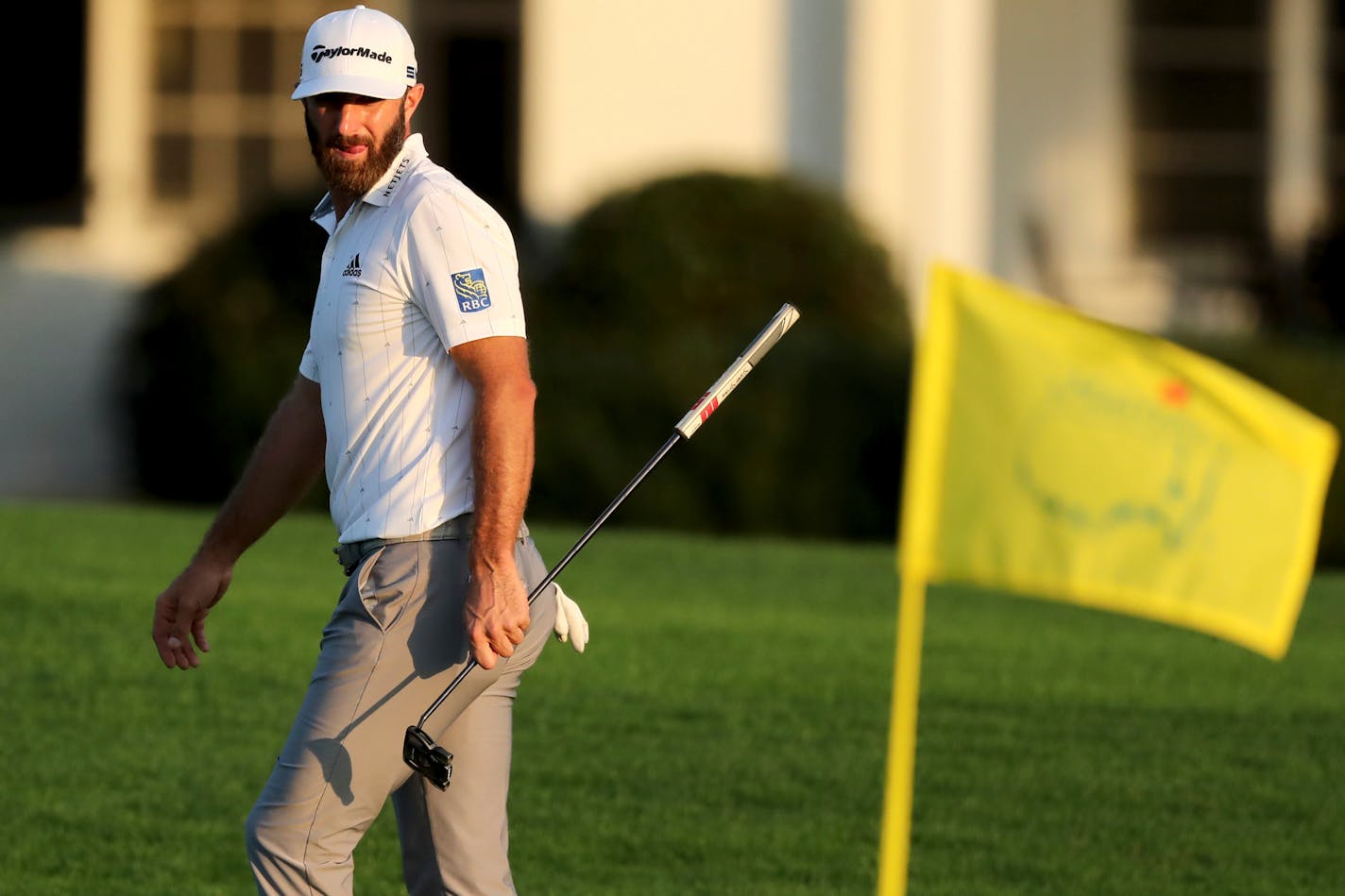 Dustin Johnson looks over his shot on the 18th green during the third round of the Masters