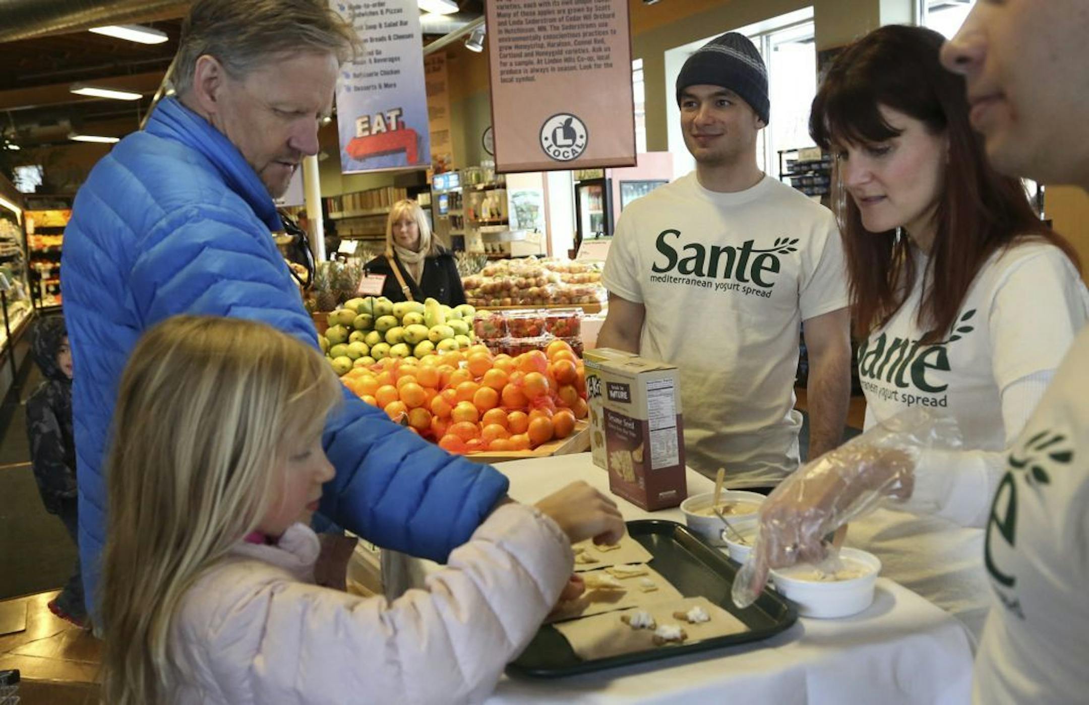 Wendy Hanson, and Teodor Scorpan, part of a team Carlson Business school students from the University of Minnesota gave samples to Anja Breiehagen, 8, and her father Per at the Linden Hills Co-op in Minneapolis Min., Friday, April 12, 2013. The is team created and are marketing Sante, a yogurt spread for their entrepreneur class.