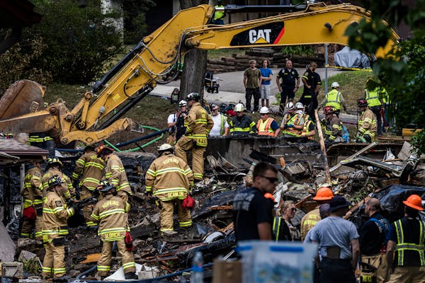 Firefighters work to recover the bodies of two occupants after the house that exploded on 21st  Avenue in Hopkins.