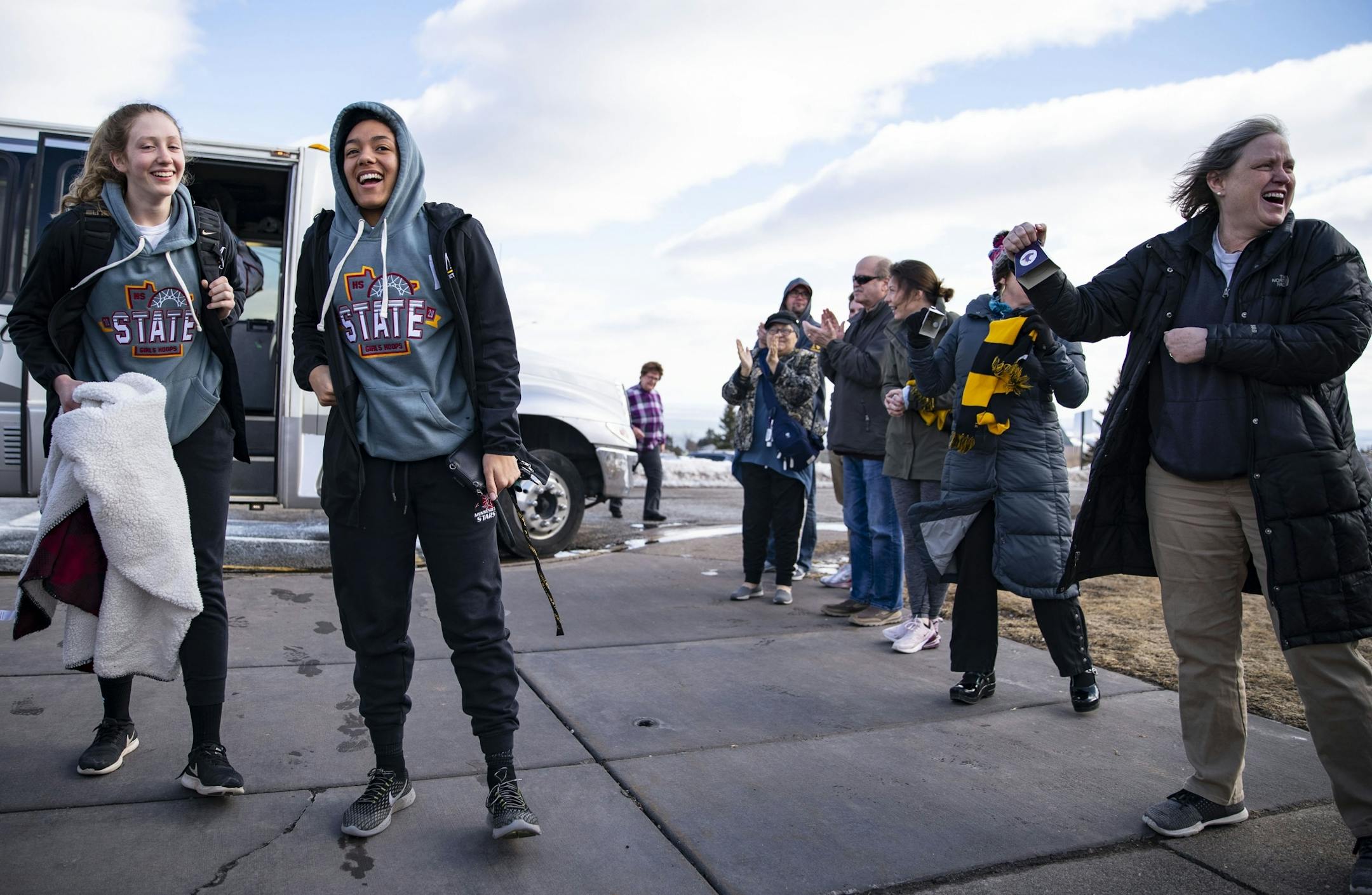 The Duluth Marshall girl's basketball team exited their bus to a line of applauding parents in the parking lot of their school after driving back from Minneapolis on Friday following the cancelation of the MSHL girl's basketball tournament.