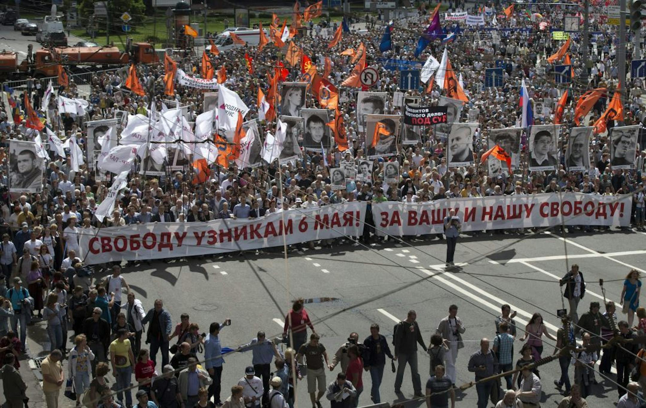 Russian opposition protesters some holding portraits of political prisoners shout anti-Putin slogans as they march through a street next to the Kremlin in Moscow on Wednesday, June 12, 2013.Thousands of Russian opposition activists are marching through Moscow decrying President Vladimir Putin's authoritarian rule and calling for the release of people they consider political prisoners. Wednesday's march is in support of 27 people who face charges related to a protest that turned violent on the ev