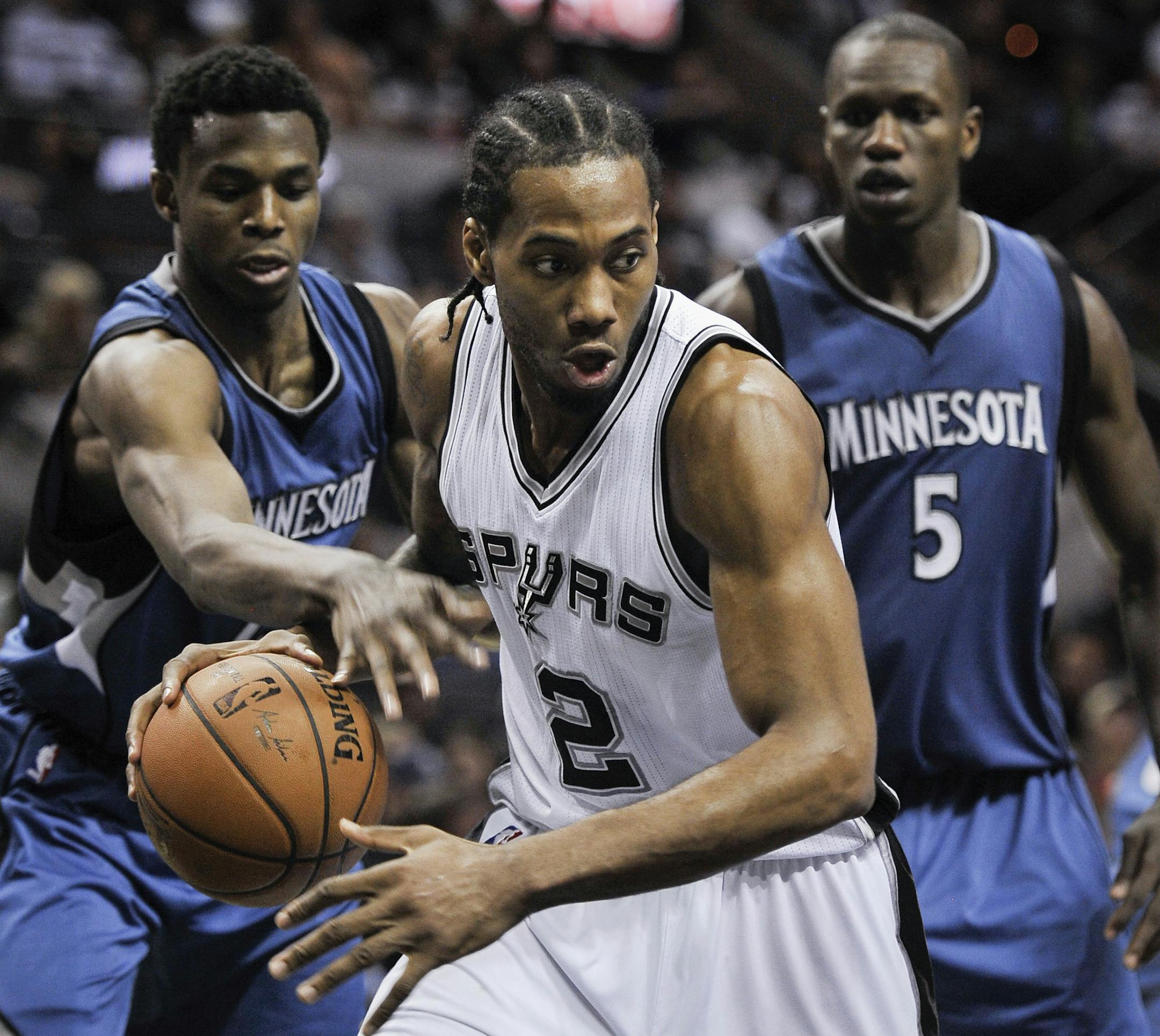 San Antonio Spurs forward Kawhi Leonard (2) tangles with Minnesota Timberwolves guard Andrew Wiggins, left, and Timberwolves center Gorgui Dieng, of Senegal, during the second half of an NBA basketball game, Sunday, March 15, 2015, in San Antonio. San Antonio won 123-97. (AP Photo/Darren Abate)