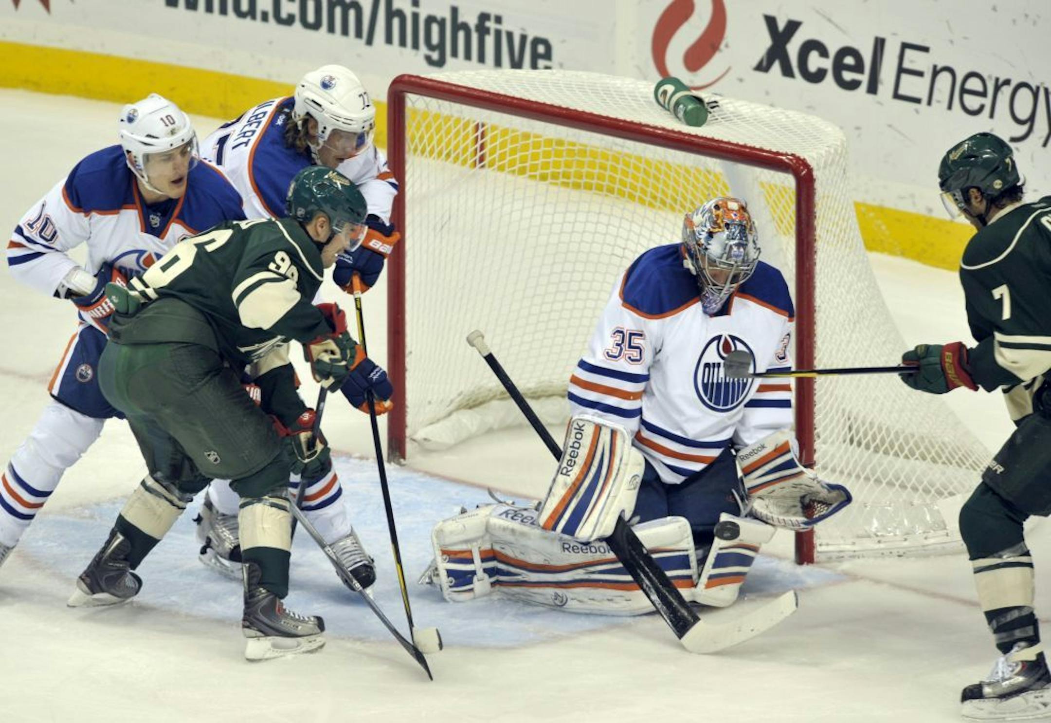 Edmonton Oilers goalie Nikolai Khabibulin, (35), of Russia, stops the shot by Minnesota Wild's Matt Cullen (7) as Oilers' defenders Shawn Horcoff, left, and Tom Gilbert, back left, hold-off the Wild's Pierre-Marc Bouchard looking for the rebound during the first period of an NHL hockey game Friday, Nov. 25, 2011, in St. Paul, Minn.