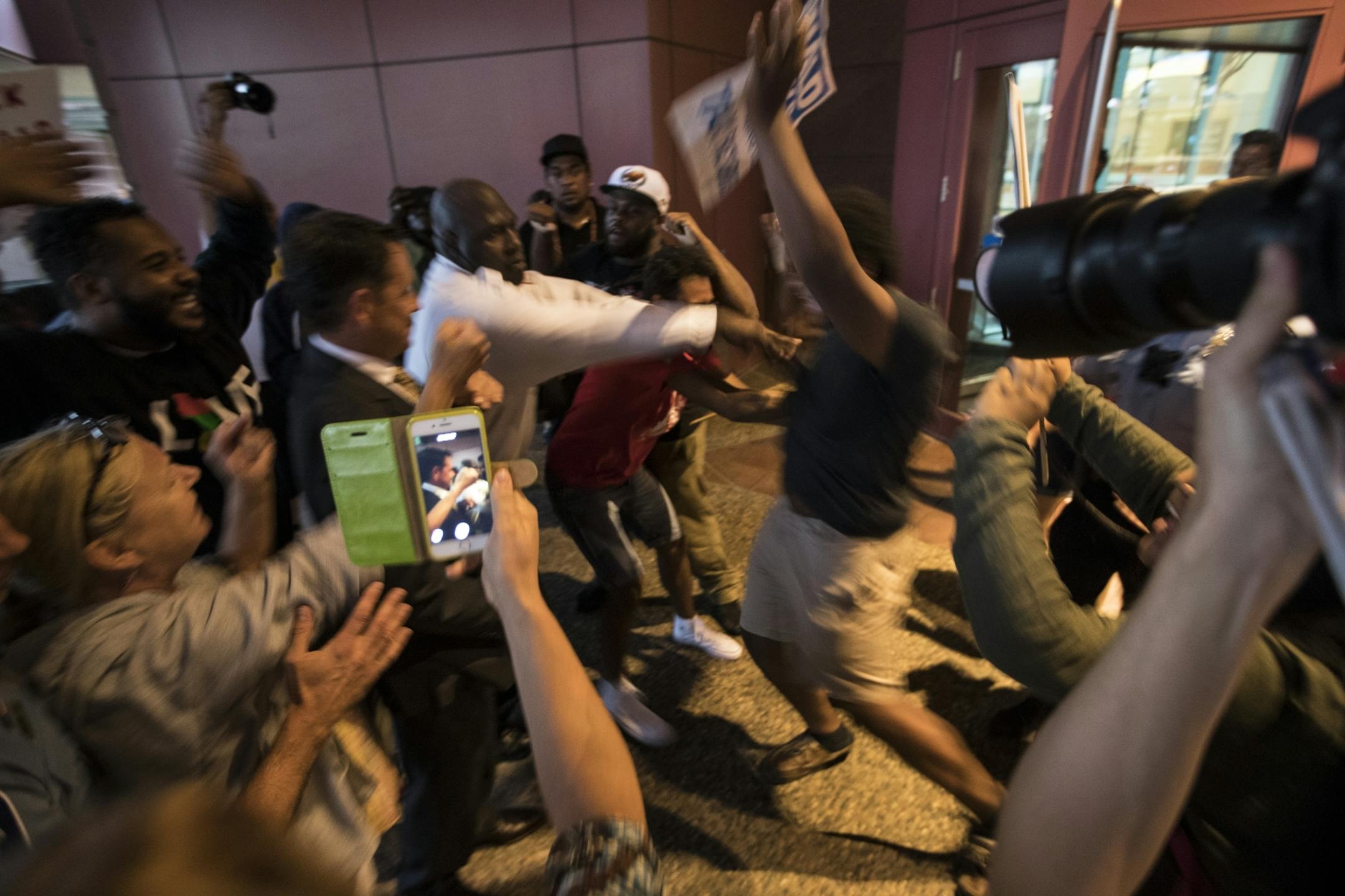 A security guard pushed a man back during a tense moment as Trump supporters were being escorted past yelling protesters at a fundraiser for the Republican presidential candidate at the Minneapolis Convention Center.