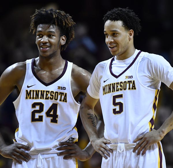 Friends and teammates Eric Curry (24) and guard Amir Coffey (5) joked around at half court during a pair of Gophers free throws in the second half aga