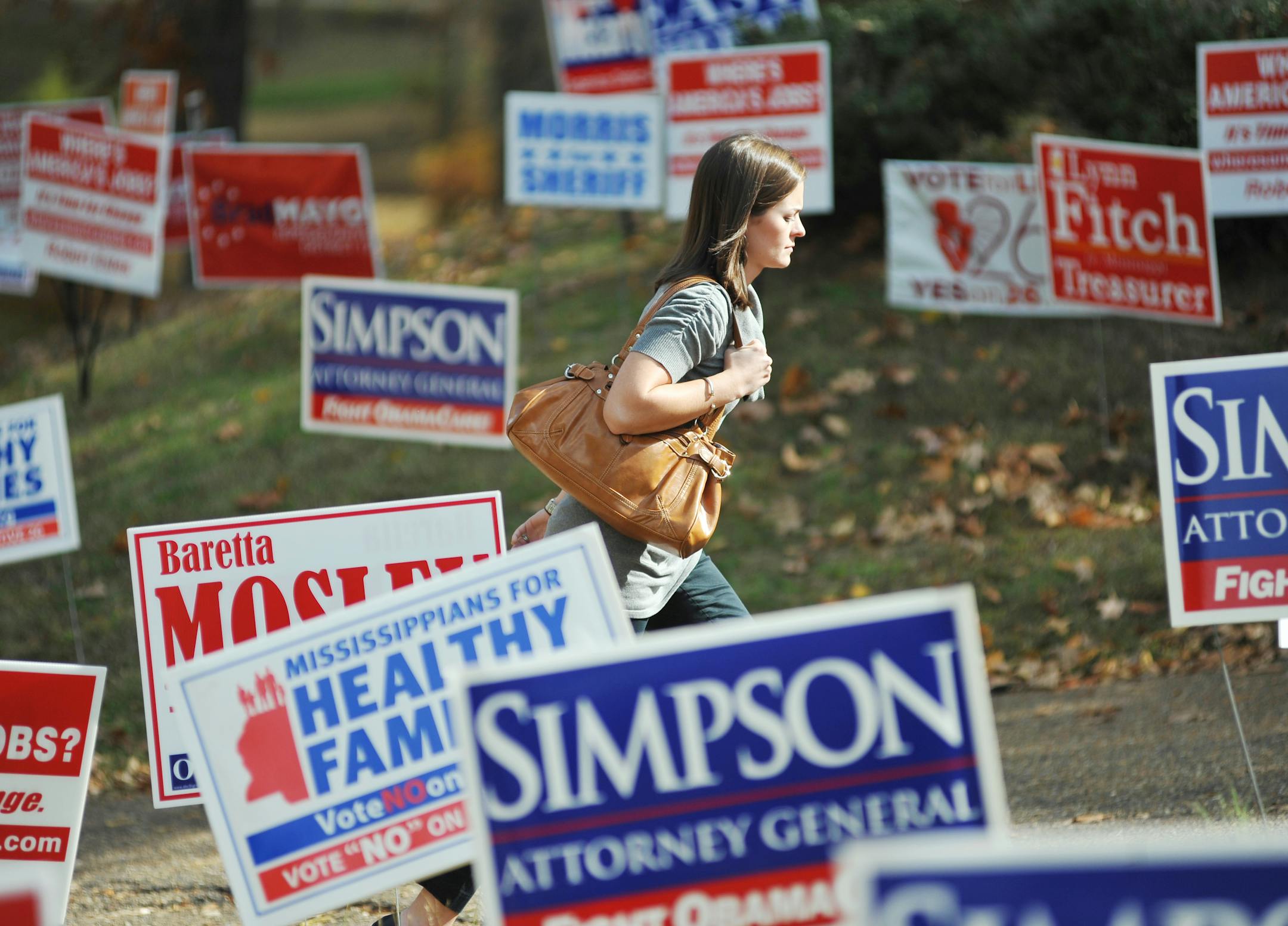 Meg Barefoot walks past campaign signs to vote at the polls at the Chamber of Commerce in Oxford, Miss. on Tuesday, Nov. 8, 2011.