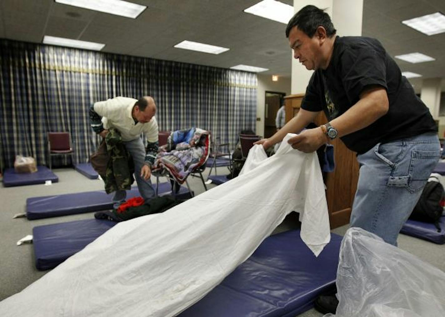 (L to R) Arlon Hedman Rodriguez and Martin Sanchez Jimenez made their beds at The First Covenant Church in Minneapolis on Tuesday evening. First Covenant has recently opened up part of the church as a homeless shelter.