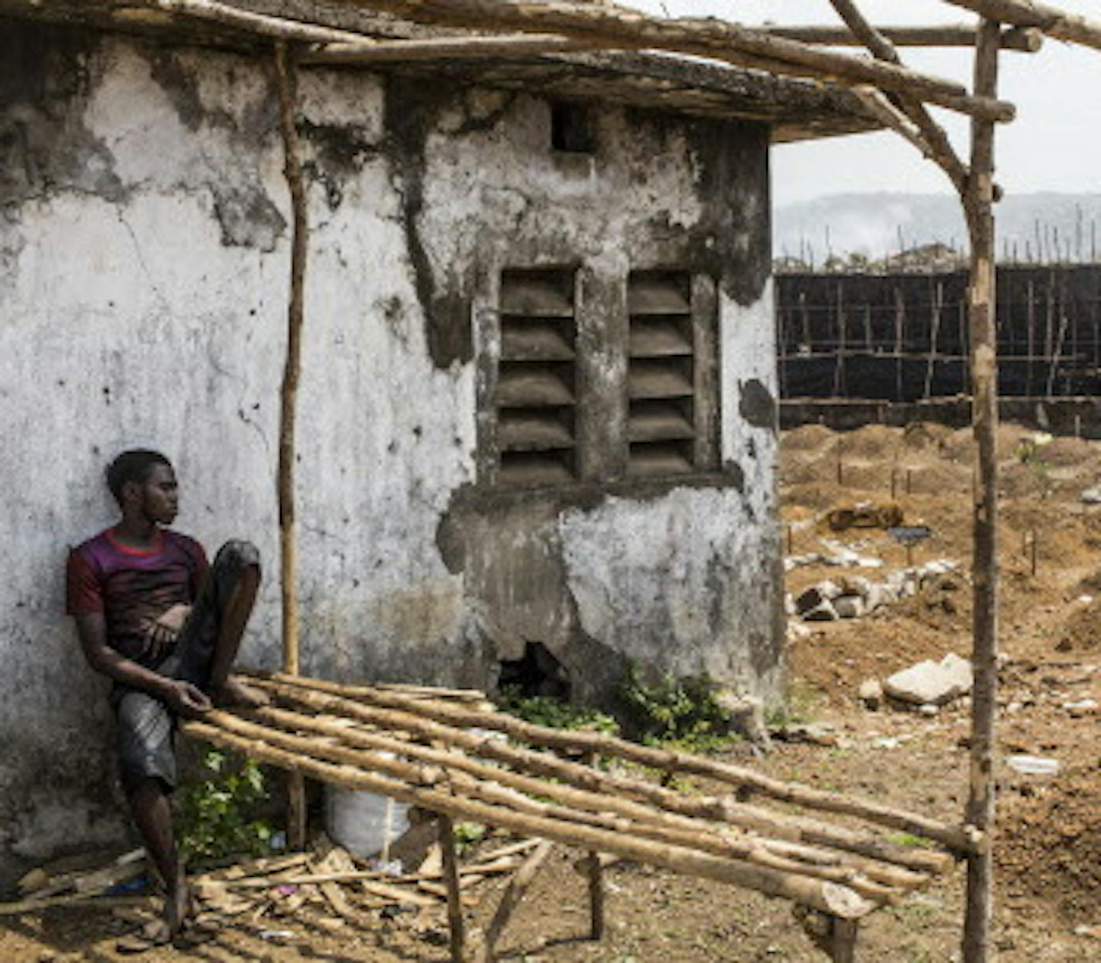 A grave digger takes a break at the King Tom cemetery, where burials for all the city's deaths from Ebola are handled by teams in protective gear, in Freetown, Sierra Leone, Feb. 21, 2015. As epidemics taper off, it is common to find new complications in the effort to reach zero cases — in Sierra Leone, the trade between cities and remote fishing villages is one of the remaining vectors for the spread of the virus. (Bryan Denton/The New York Times)