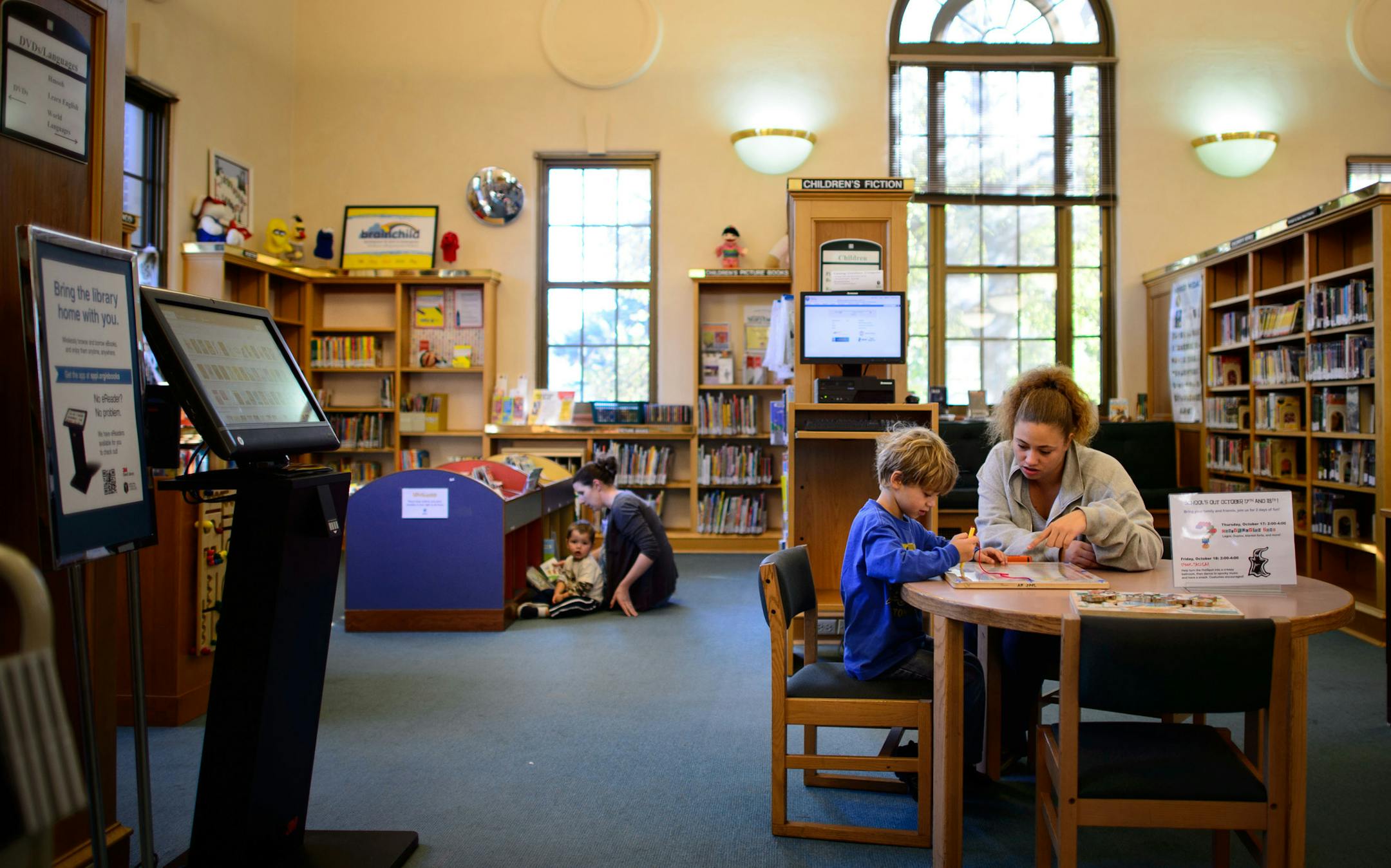 Belinda Nevils, and her son Nathan, 4, right played an educational game while Christne Wainio read to her son Gilbert, 2, left, in the Arlington Hills Library. The St. Paul Public Library System is seeking a new owner for the Arlington Hills Library, one of three Carnegie libraries in the city and built in 1916 and listed on the National Register of Historic Places, who will retain it as a neighborhood and cultural asset. The library itself is moving to modern quarters on the East SIde. Thursday