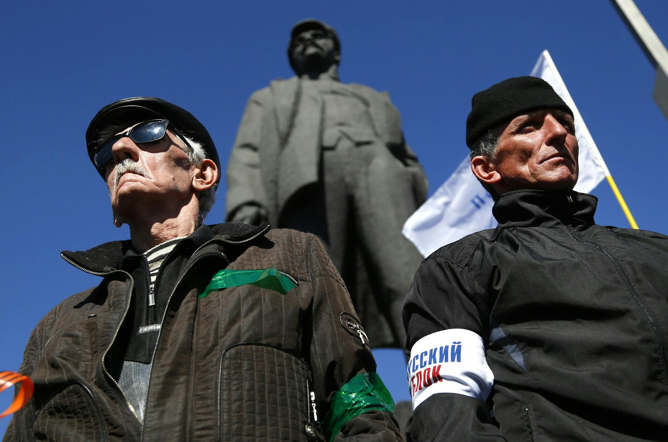 Activists stand guard during a pro Russian rally at a central square in Donetsk, eastern Ukraine, Sunday, March 23, 2014. About 5,000 people demonstrated in Donetsk in favor of holding a referendum on secession and absorption into Russia similar to Crimea's. A statue of Lenin, Soviet Union's first president, is seen in the background. (AP Photo/Sergei Grits)