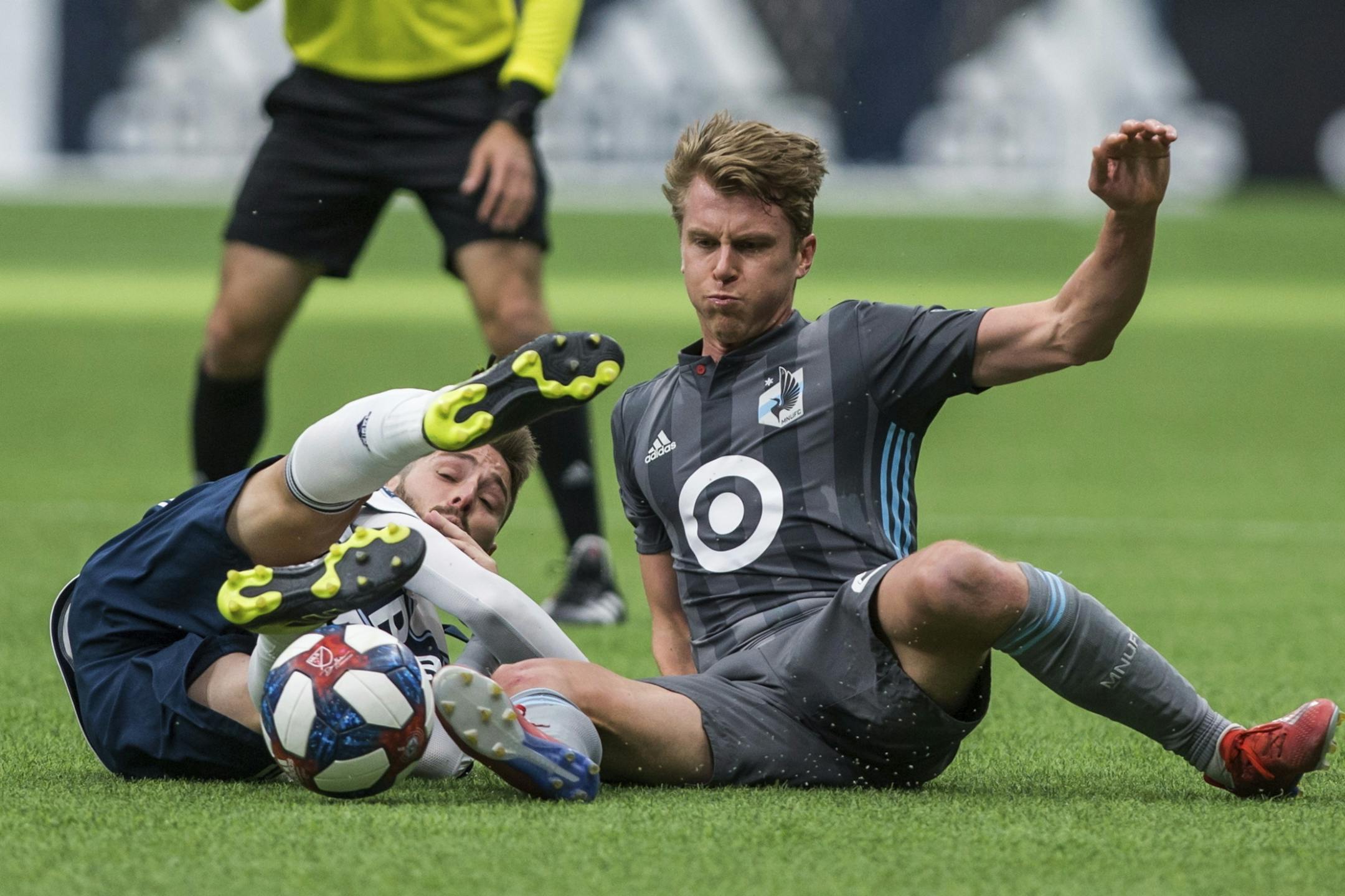 Vancouver Whitecaps' Jon Erice, left, is tackled by Minnesota United's Rasmus Schuller during the first half of an MLS soccer match Saturday, March 2, 2019, in Vancouver, British Columbia.