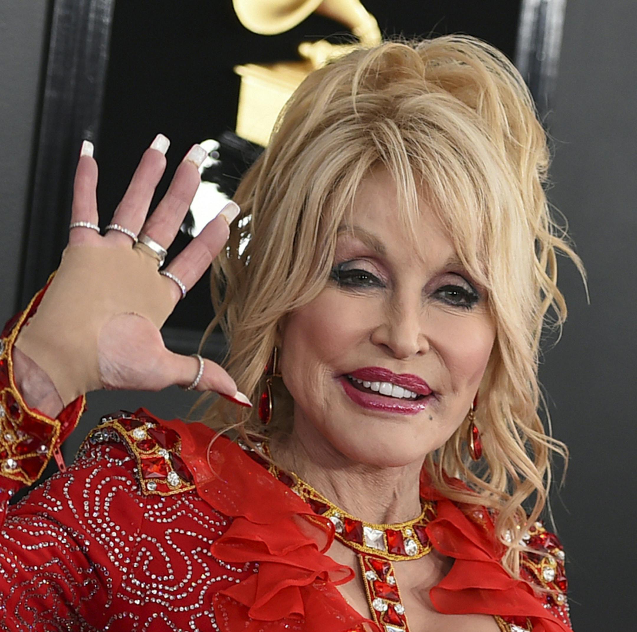 FILE - In this Feb. 10, 2019 file photo, Dolly Parton arrives at the 61st annual Grammy Awards at the Staples Center in Los Angeles. The CMAs announced Monday, August 19, 2019 that “special guest hosts” Dolly Parton and Reba McEntire will join Carrie Underwood during the Nov. 13 event. The organization says the show will celebrate “legendary women in Country Music throughout the ceremony.” (Photo by Jordan Strauss/Invision/AP, File)