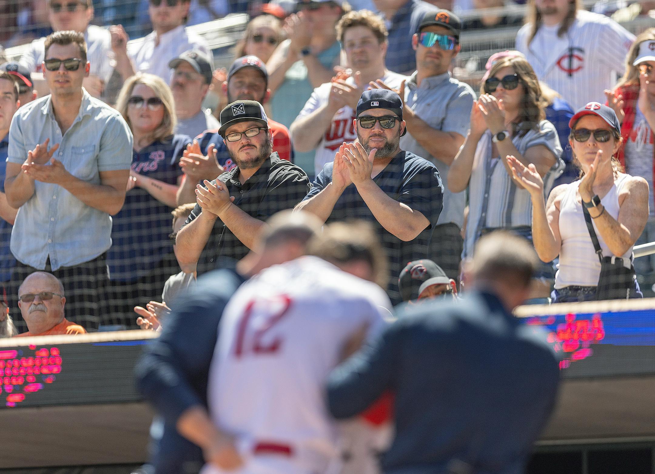 Twins fans applaud Minnesota Twins third baseman Kyle Farmer (12) as he gets help to the dugout after getting hit with a pitch during the bottom of the fourth inning.