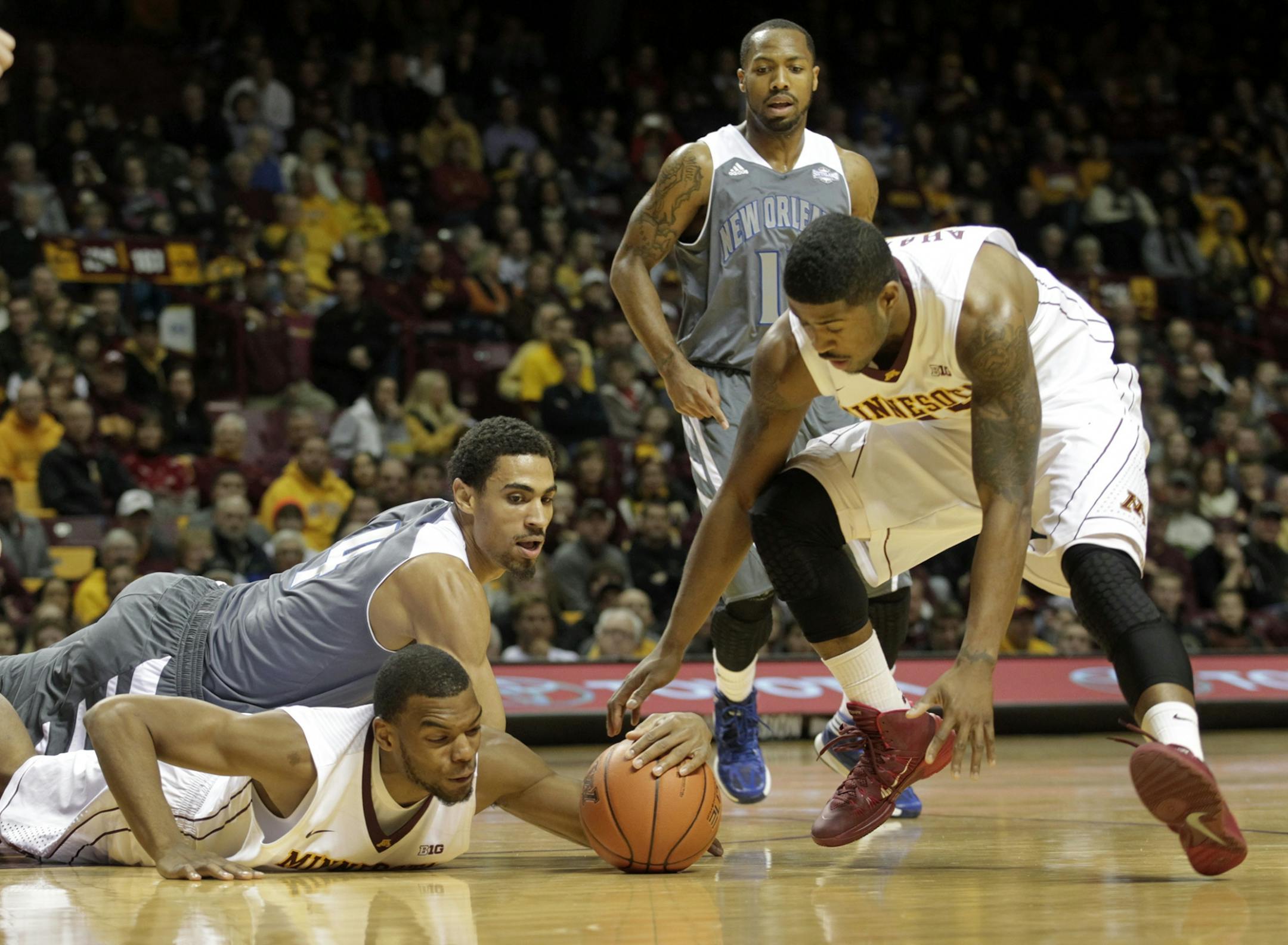 Minnesota's Andre Hollins, bottom, tries to control the loose ball with teammate Maverick Ahanmisi, right, against New Orleans forward Cory Dixon (4) during the first half of an NCAA college basketball game, Saturday, Dec. 7, 2013, in Minneapolis. New Orleans guard Isaac Mack (11) looks on during the play. Minnesota won 80-65.