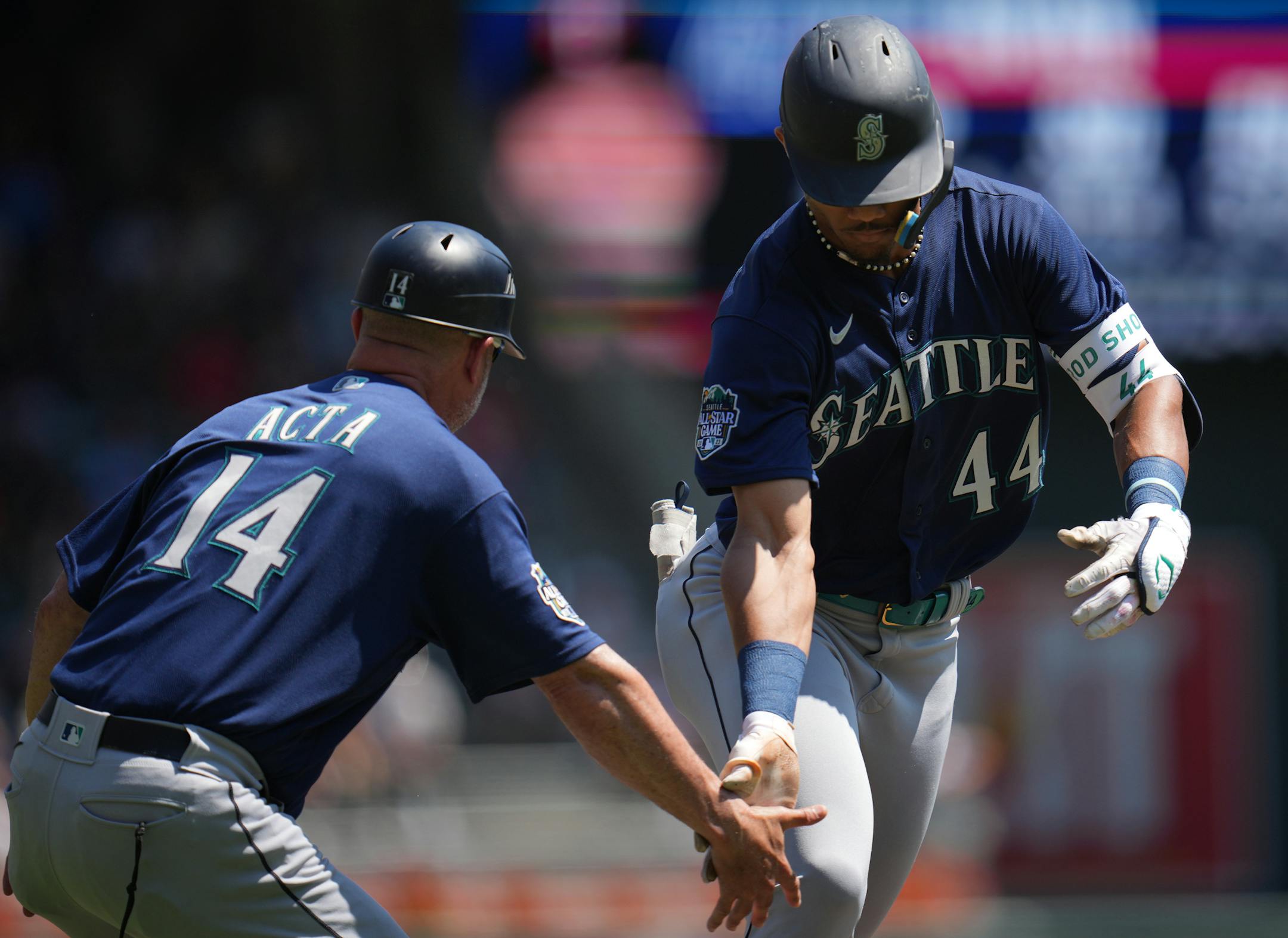 Seattle Mariners center fielder Julio Rodriguez (44) is congratulated by Seattle Mariners third base coach Manny Acta (14) as he rounds the bases on a home run in the third inning.