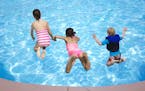 Kids jumping into the swimming pool.