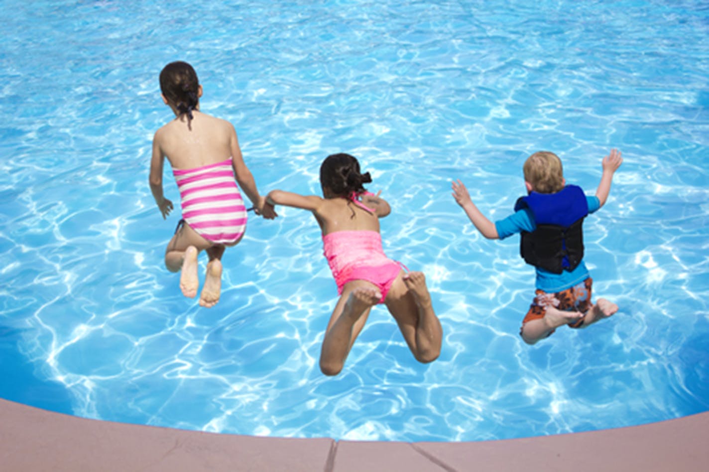 Kids jumping into the swimming pool.