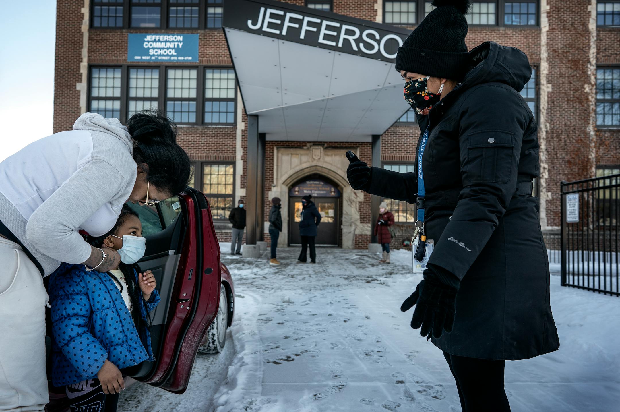 Vanisa Ford left helped her daughter Elizabeth Smith 4, put on he mask as Jefferson Community School staff member Gabriela Boley Hernandez waited to walk her in to the building Monday February 8, 2021 in Minneapolis.
