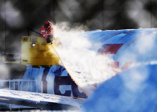 A worker deiced a FedEx plane near Minneapolis-International Airport after the heavy snowfall