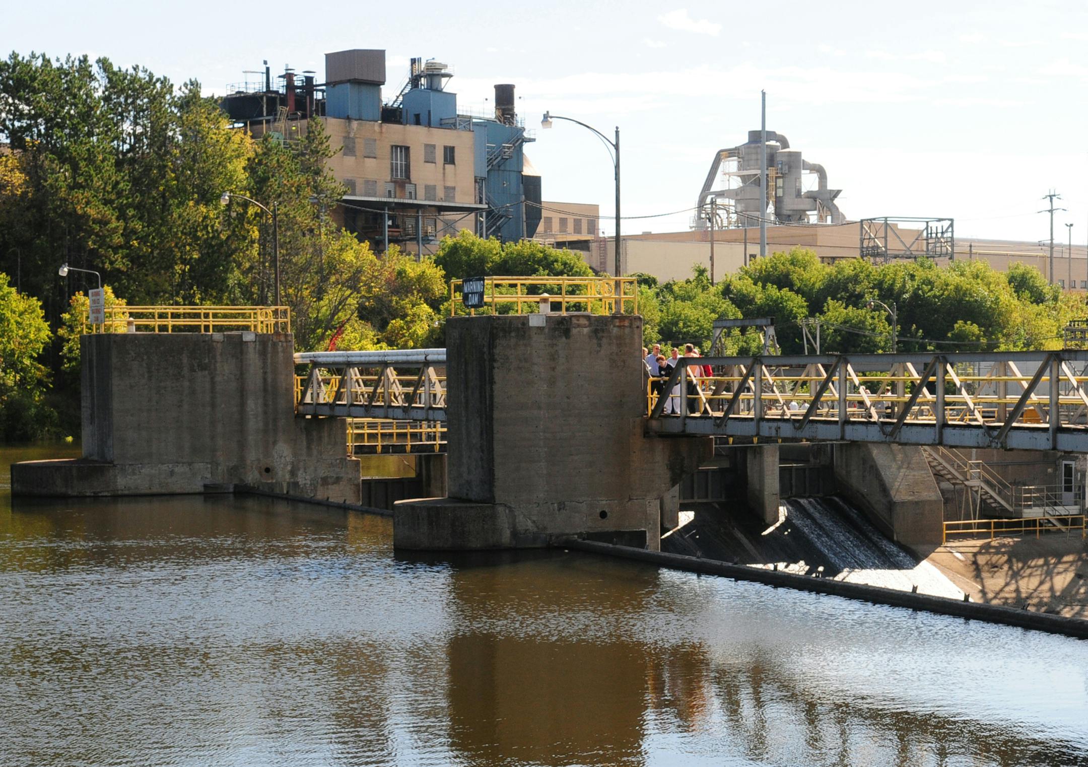 Brainerd Dispatch/Steve Kohls Brainerd city officials walk across a span of the Wausau Paper dam Tuesday during a Brainerd Public Utilities tour of the facility. Brainerd is considering buying the property to generate electricity for the city.