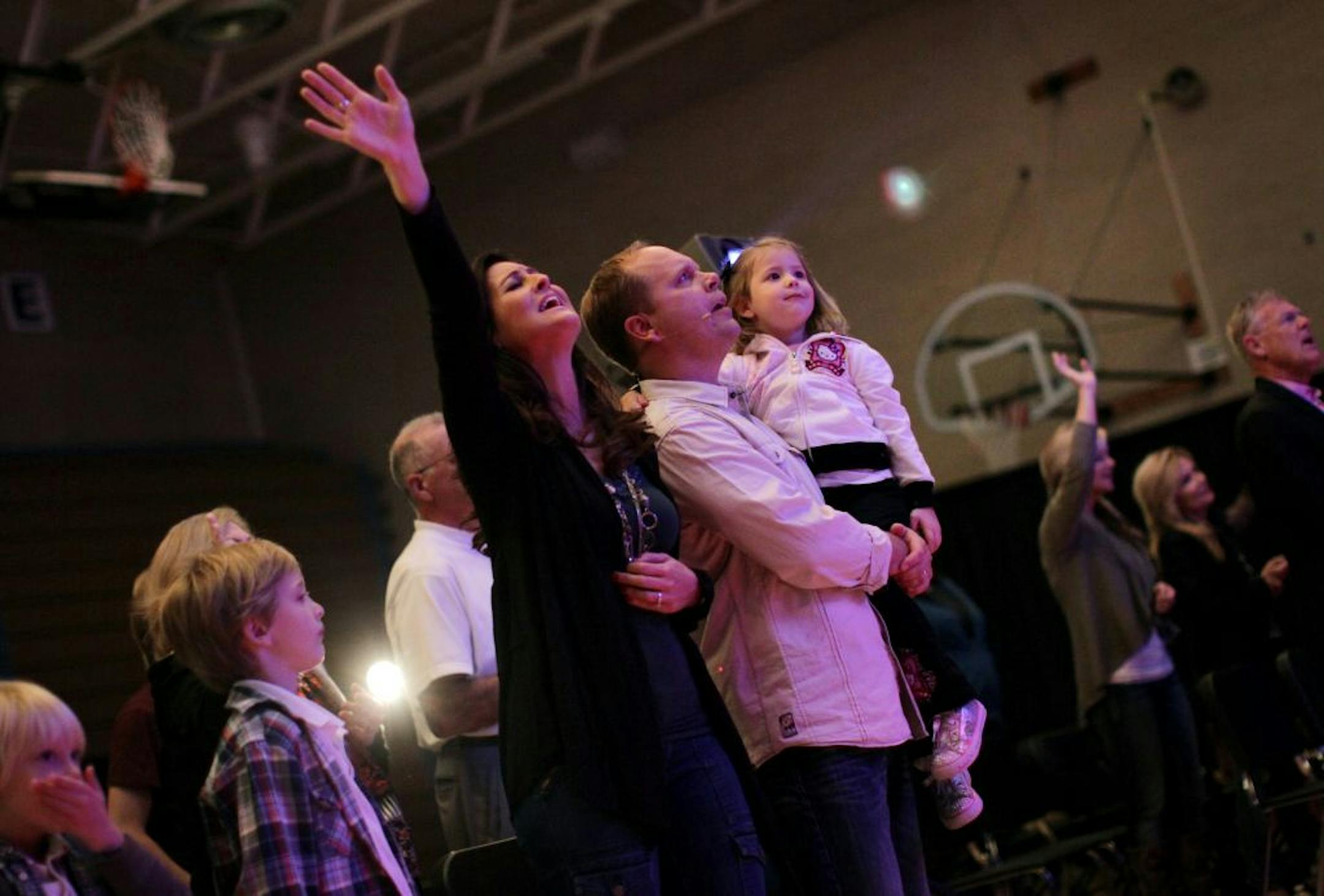 Authentic Life Church pastor Ken Olson held his daughter Katherine as he, and his wife Sara Olson, sang during the worship service during a Sunday service at the Hopkins West Junior High School building in Minnetonka, Minn., October 23, 2011. The church sets up and breaks down a full church set-up each Sunday at the school.