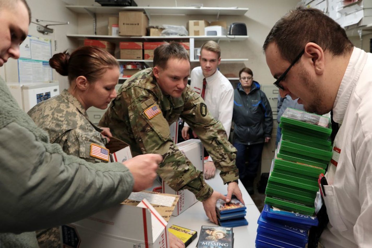 From left, Sgt. Banchee Barnett, Spc. Deanna Rice, Spc. Richard Polson, and Pawn America general manger Austin Dewanz, pack boxes of DVDs, video games, and video game systems to send to troops in Kuwait as more are brought in.