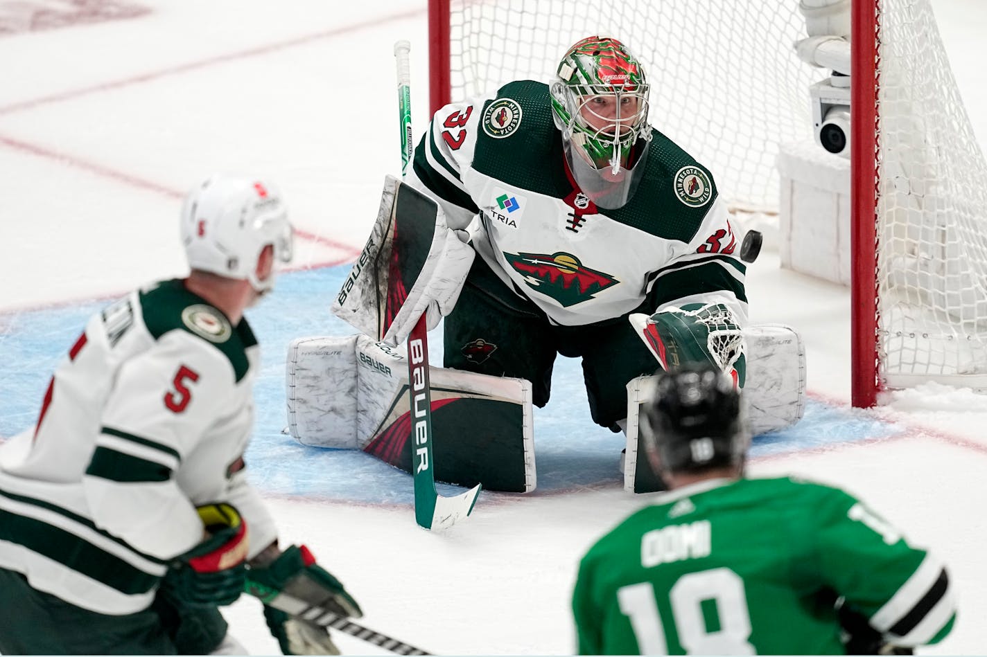 Minnesota Wild goaltender Filip Gustavsson (32) reaches out to glove a shot as Jake Middleton (5) and Dallas Stars center Max Domi (18) look on in overtime of Game 1 of an NHL hockey Stanley Cup first-round playoff series, Tuesday, April 18, 2023, in Dallas. (AP Photo/Tony Gutierrez)