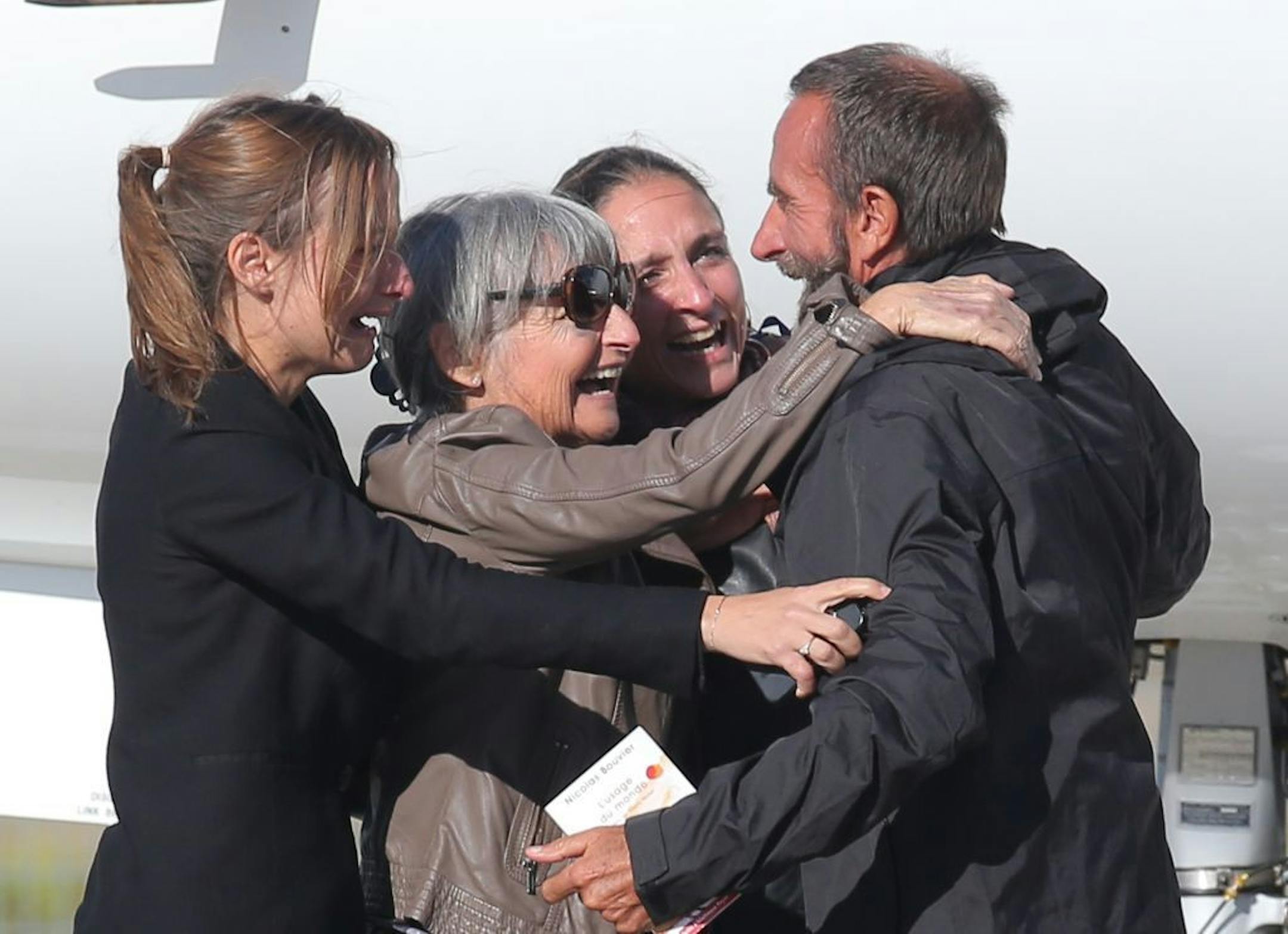 Released French hostage Daniel Larribe, right, hugs his wife and two daughters upon his arrival at the Villacoublay military airbase, outside Paris, Wednesday, Oct. 30, 2013.