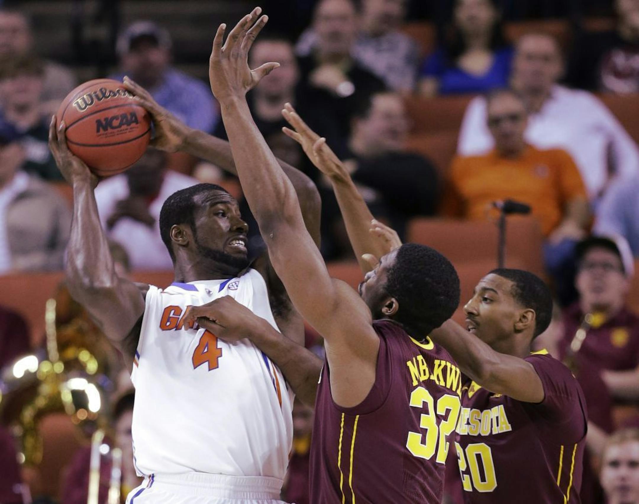 Minnesota defenders Trevor Mbakwe (32) and Austin Hollins (20) pressure Florida's Patric Young (4) during the first half of a third-round game of the NCAA college basketball tournament Sunday, March 24, 2013, in Austin, Texas.