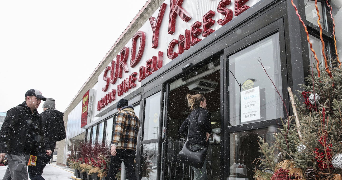 People enter The Surdyk's liquor store in the snow in Minneapolis on Sunday, March 12, 2017. The liquor store has gotten a head start on opening for business on Sundays. Surdyk's, a longtime liquor and cheese store in northeast Minneapolis, opened for business Sunday, despite Minnesota's new Sunday liquor sales law not taking effect until July. (Xavier Wang/Star Tribune via AP) ORG XMIT: MIN2017031313322829