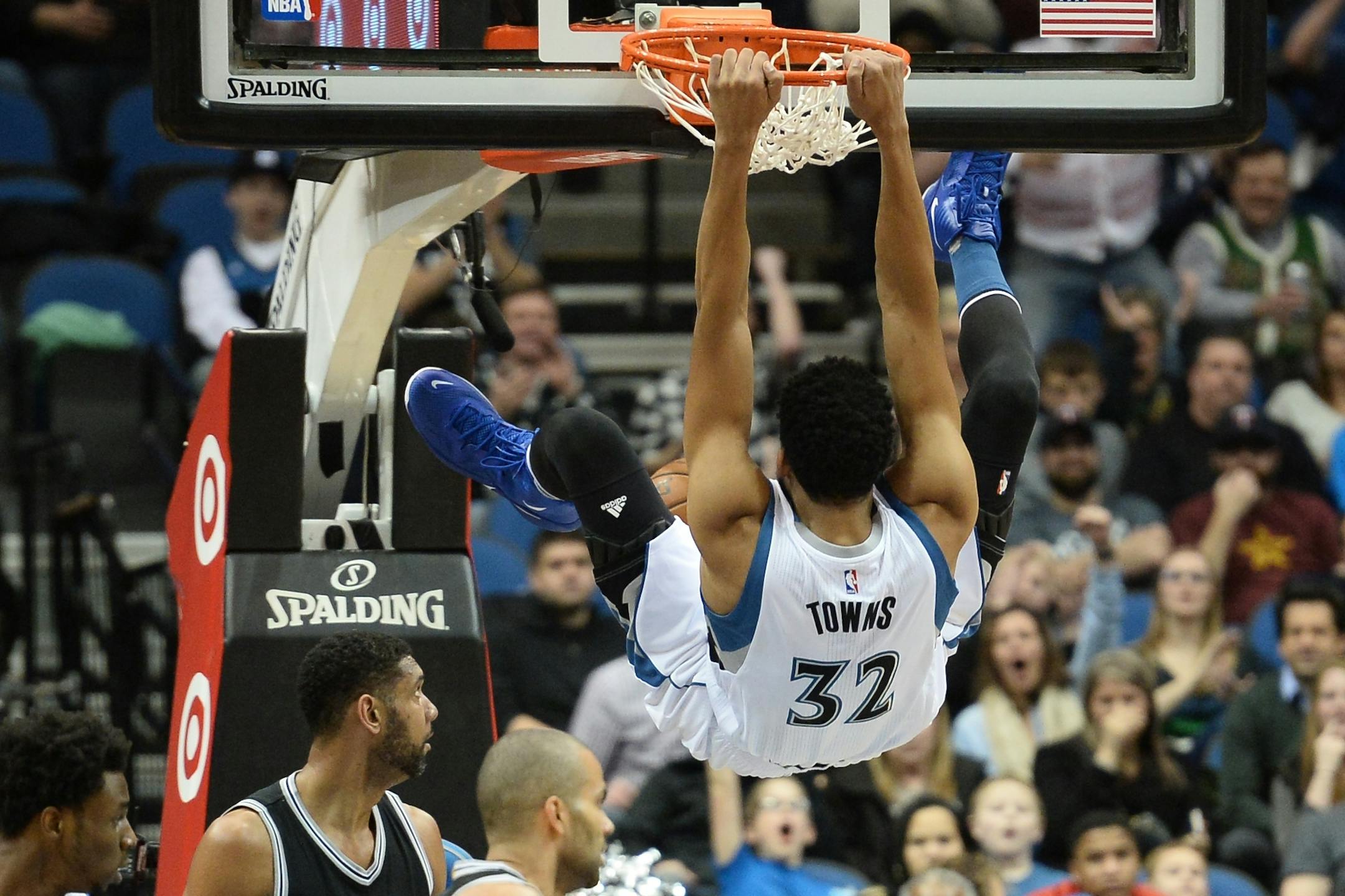 Minnesota Timberwolves center Karl-Anthony Towns (32) hung on the rim after dunking on the Spurs in the first quarter.