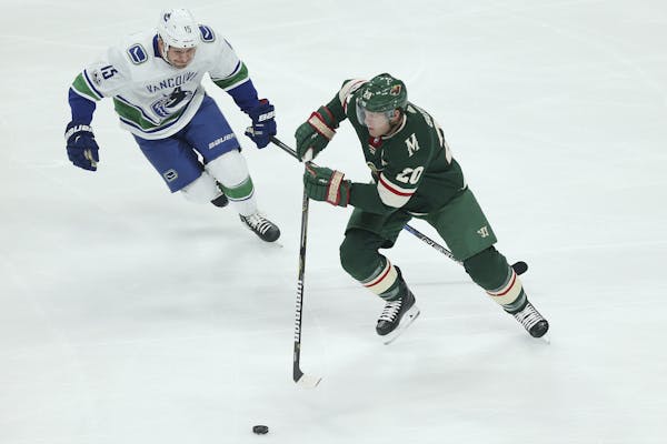Minnesota Wild's Ryan Suter (20) controls the puck against Vancouver Canucks' Derek Dorsett (8) in the first period of an NHL hockey game Tuesday, Oct