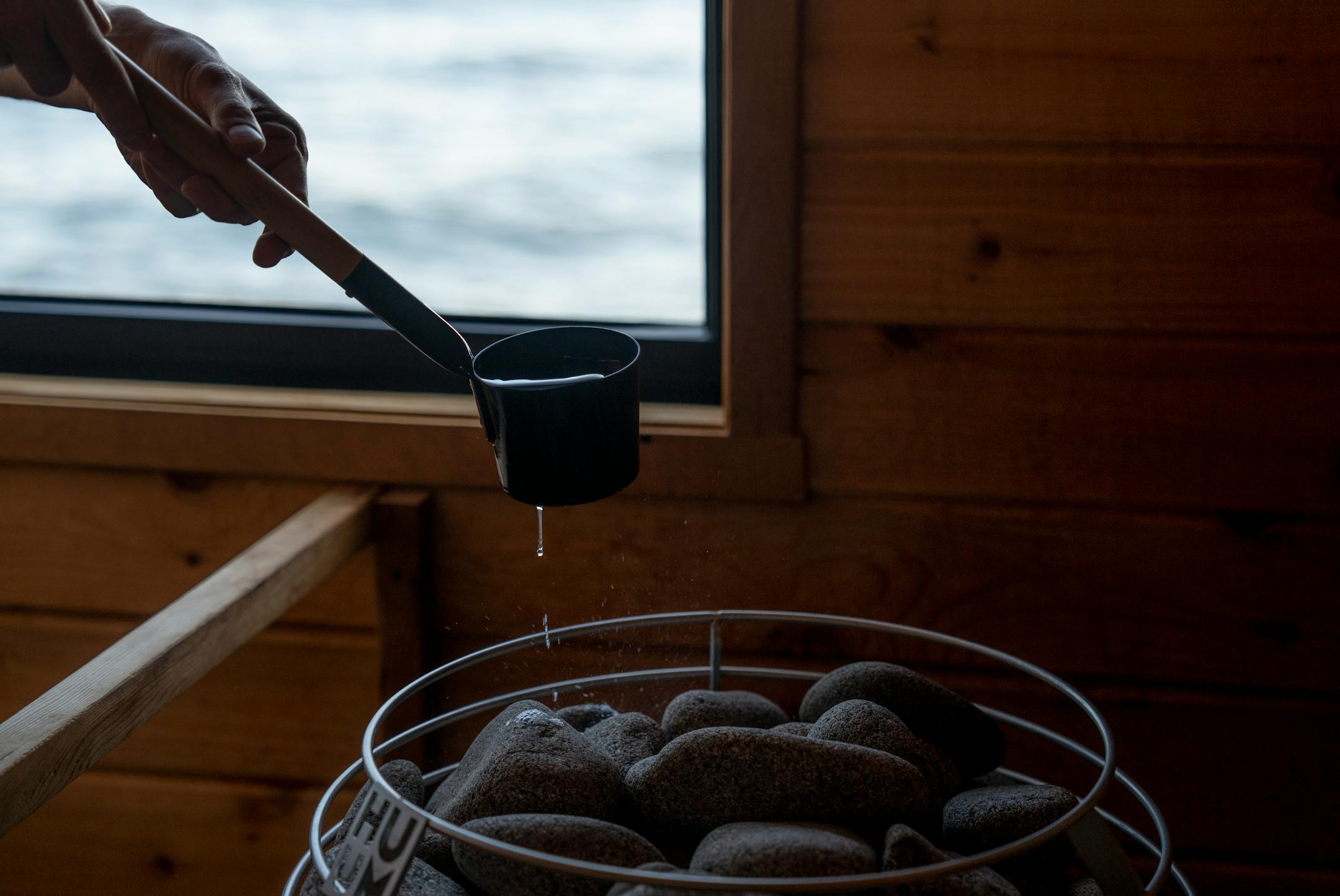 Shaun Tudor paddles water onto the rocks to generate steam while enjoying a sauna session at Sisu and Löyly Sauna.