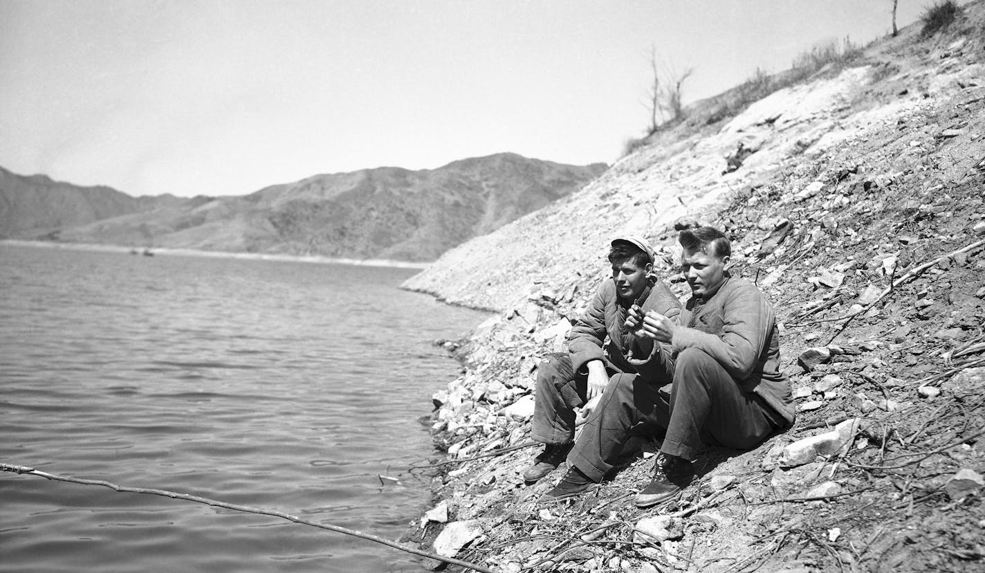 Pfc. Harold E. Belden, left, of Pomona, Calif. and Pvt. J.C. Hatcher, of Birmingham, Ala. prisoners of war in North Korean Prison Camp #5 at Pyokdong on March 1, 1952, try their luck with an improvised fishing rod on stream running through the camp. (AP Photo/Frank Noel ) ORG XMIT: APHS292351