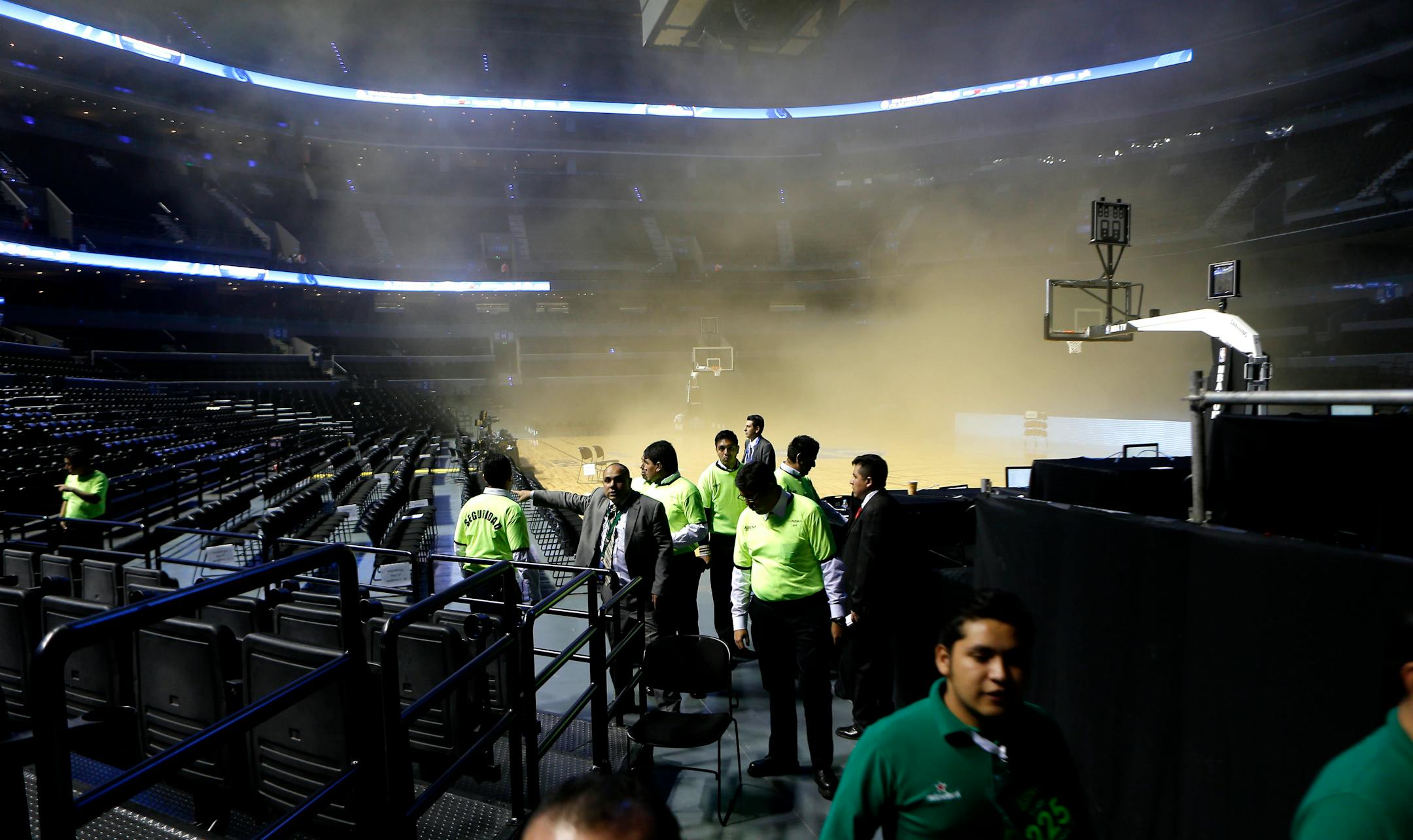 People leave as smoke engulfs the basketball court during a regular season NBA match between the Minnesota Timberwolves and the San Antonio Spurs in Mexico City, Wednesday, Dec. 4, 2013.
