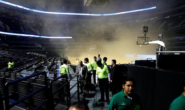 People leave as smoke engulfs the basketball court during a regular season NBA match between the Minnesota Timberwolves and the San Antonio Spurs in M