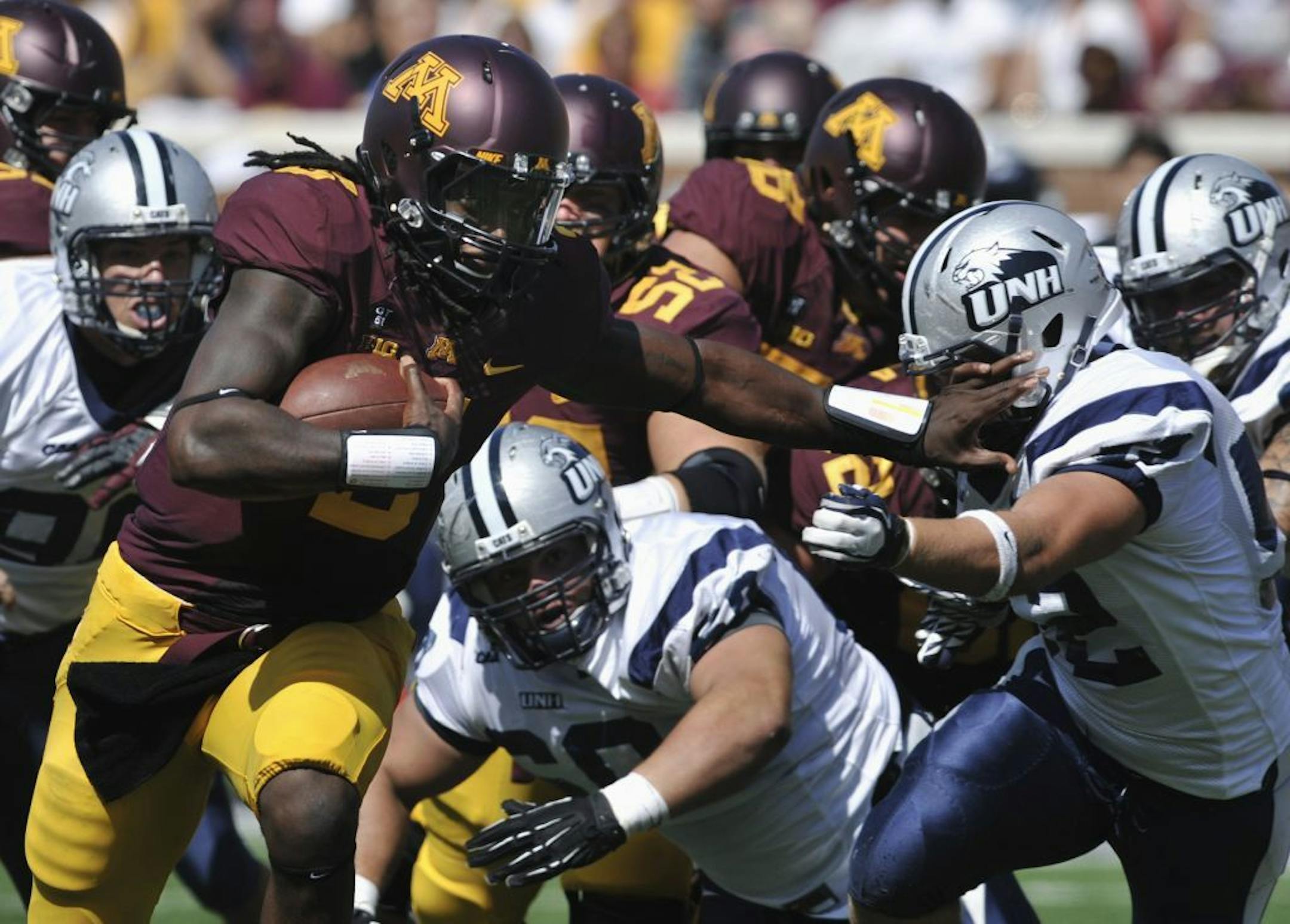 Minnesota quarterback MarQueis Gray, left, gives New Hampshire's Matt Evans, right, a stiff-arm on a touchdown run during the second quarter of an NCAA college football game, Saturday, Sept. 8, 2012, in Minneapolis. It is Gray's second touchdown of the first half.