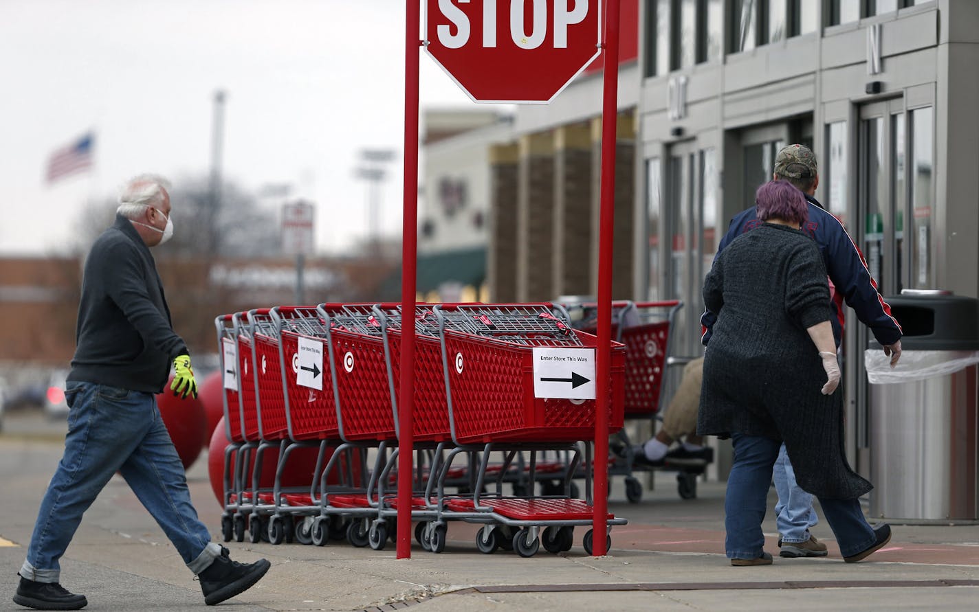 Grocery carts set up a path for shoppers at the entrance to a Target store Monday, April 6, 2020, in Bloomington, Minn., where an employee keeps count of customers as the number allowed in is limited to help reduce the spread of the coronavirus. The new coronavirus causes mild or moderate symptoms for most people, but for some, especially older adults and people with existing health problems, it can cause more severe illness or death. (AP Photo/Jim Mone)