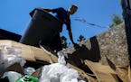 Ryan Hubner of 1-800-Got-Junk offloads a trashcan onto a garbage truck at the Lake Hiawatha cleanup spot. ] Timothy Nwachukwu &#x2022; timothy.nwachuk