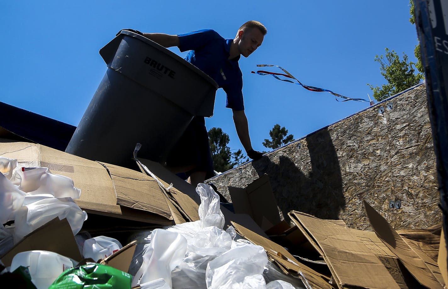 Ryan Hubner of 1-800-Got-Junk offloads a trashcan onto a garbage truck at the Lake Hiawatha cleanup spot. ] Timothy Nwachukwu &#x2022; timothy.nwachukwu@startribune.com Volunteers celebrate after collecting 9536 total pounds of trash along Minnehaha Creek at Lake Hiawatha Park on Saturday, July 24, 2016.