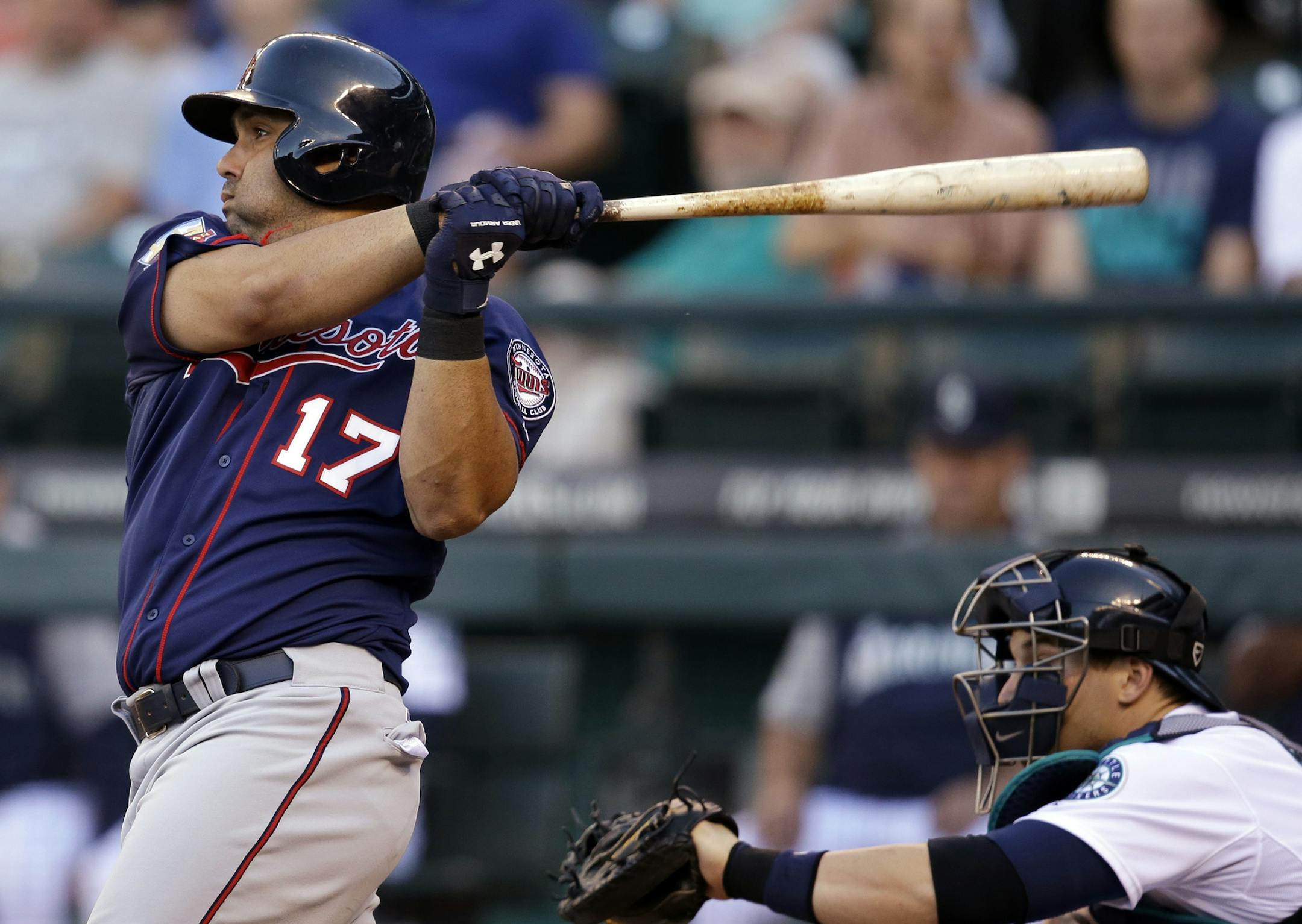 Minnesota Twins' Kendrys Morales (17) doubles in a run as Seattle Mariners cacher Mike Zunino looks on in the first inning of a baseball game Wednesday, July 9, 2014, in Seattle. (AP Photo/Elaine Thompson)