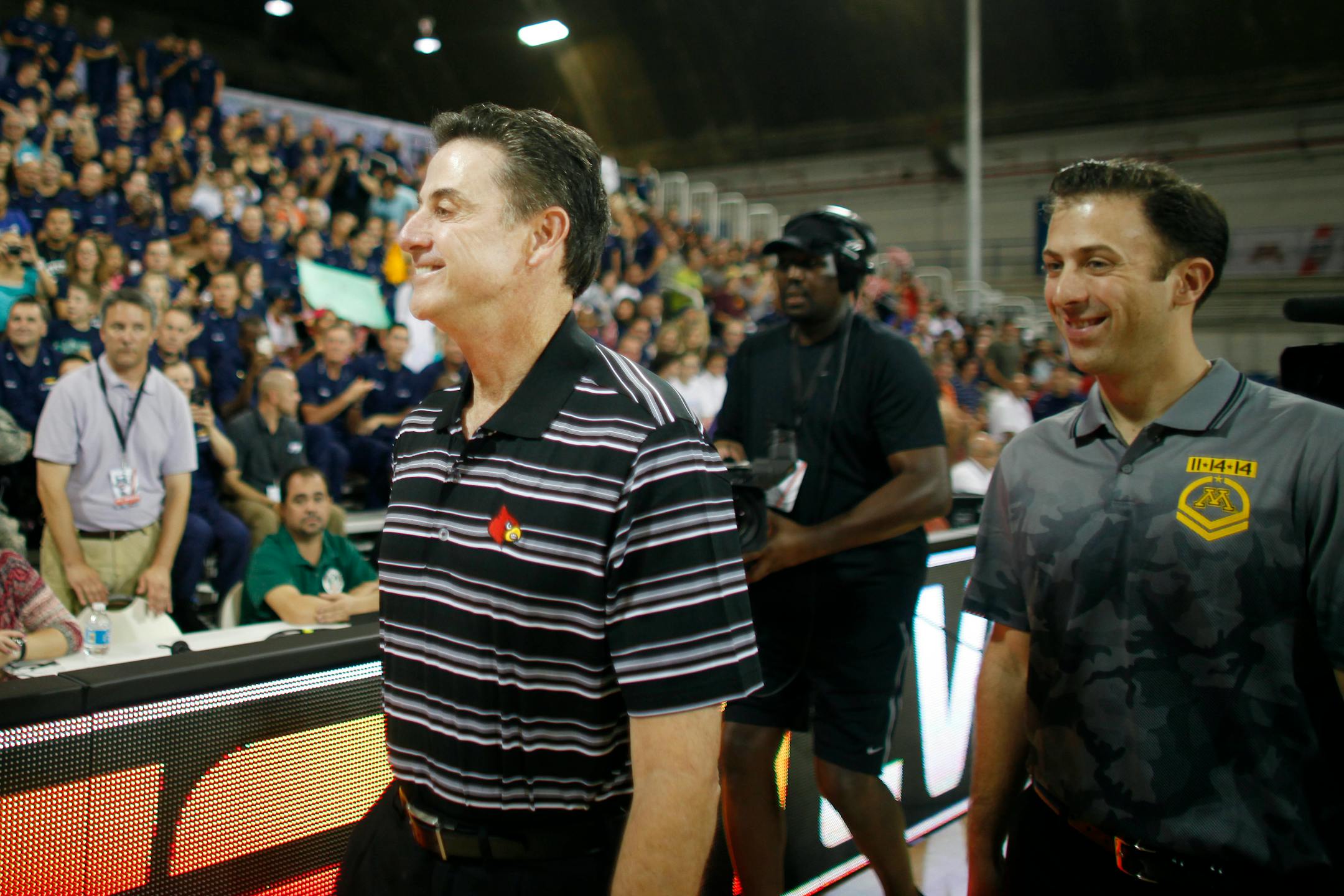 Louisville head coach Rick Pitino, left, walks with his son, Minnesota head coach Richard Pitino, as they arrive to the court for a NCAA college basketball Armed Forces Classic game inside a hangar at the United States Coast Guard Air Station base in Aguadilla, Puerto Rico, Friday, Nov. 14, 2014. (AP Photo/Ricardo Arduengo)