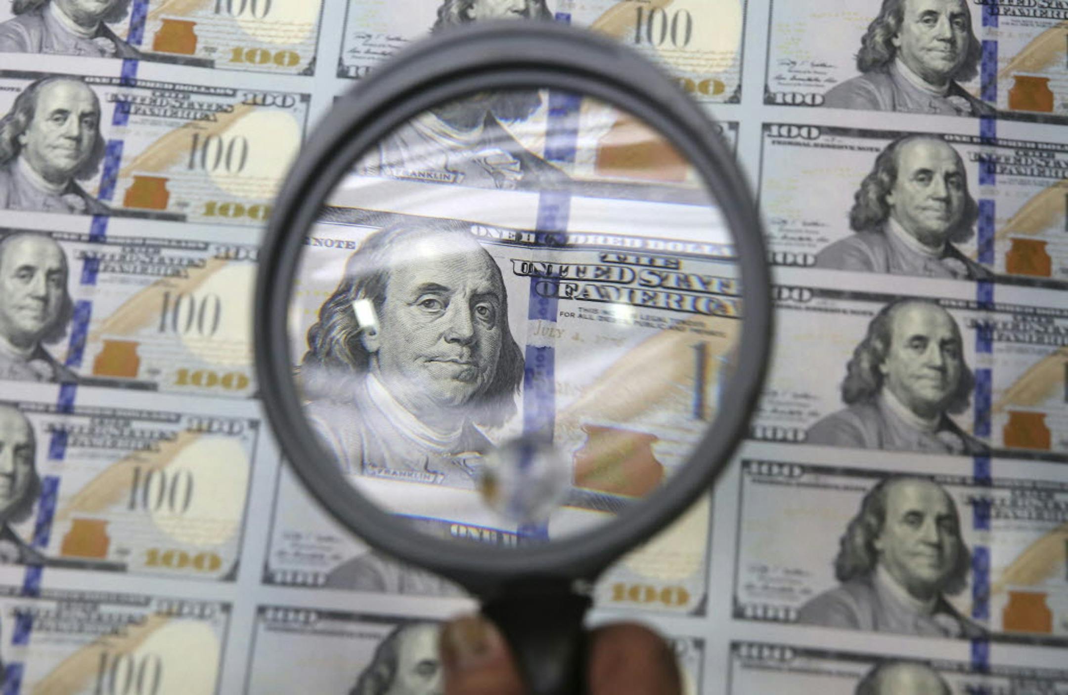 A sheet of uncut $100 bills is inspected during the printing process at the Bureau of Engraving and Printing Western Currency Facility in Fort Worth, Texas.